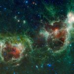 A colorful nebula in space with blue stars and orange and green clouds.