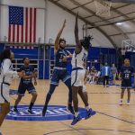 Two basketball players skirmish at the basketball hoop.
