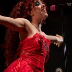 Chappell Roan singing into a microphone arms stretched to the side