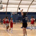 Basketball player in a navy jersey shoots the ball during a game.