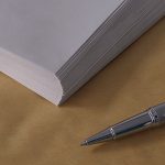 A silver pen near a stack of envelopes