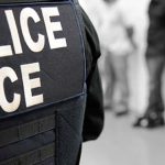 An ICE officer oversees an immigration enforcement operation