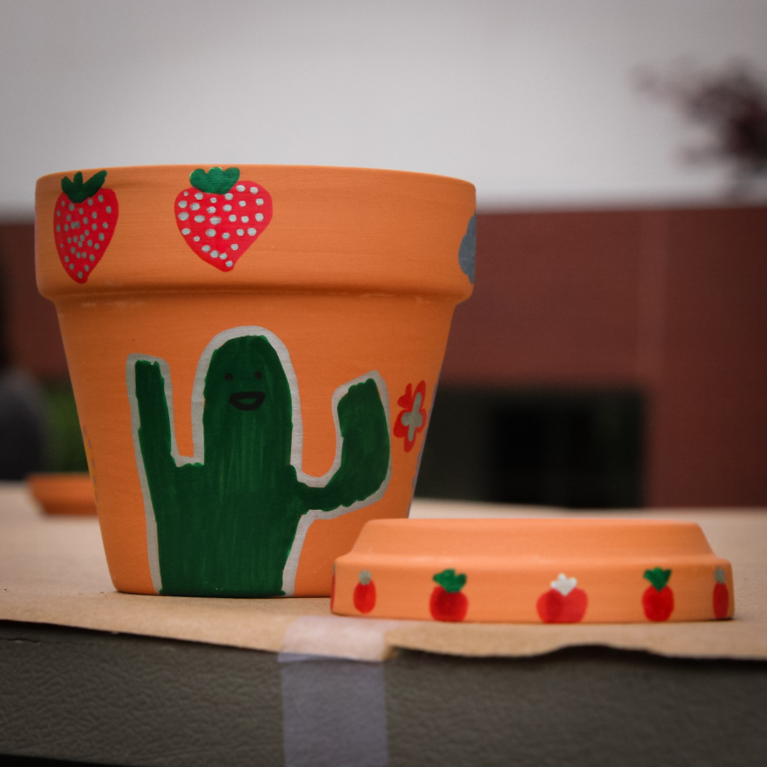 A small pot with a happy cactus on the side