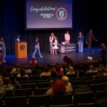 A woman walks across the stage to receive a certificate.