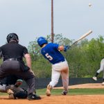 Baseball player hits ball past the pitcher.