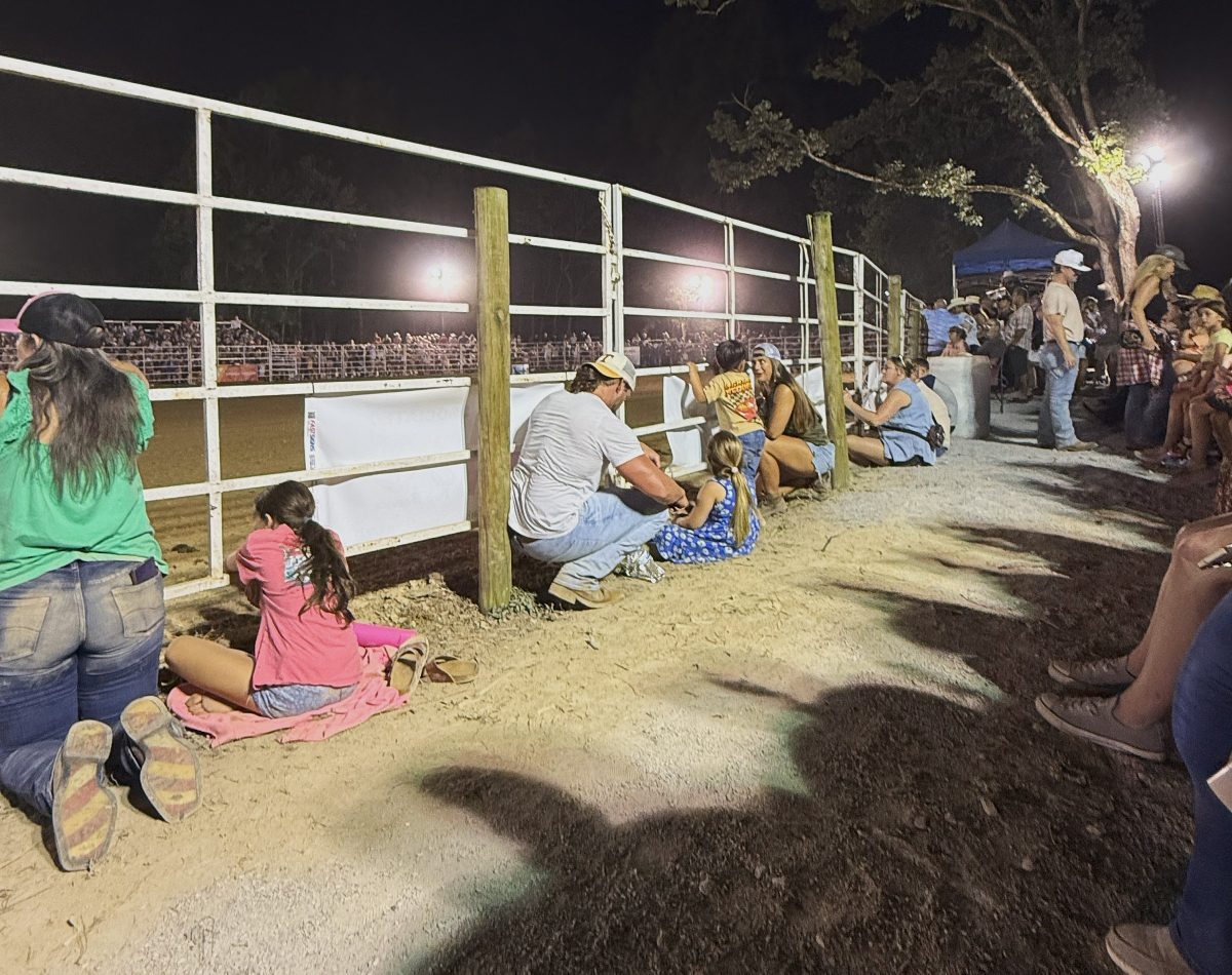 People sitting in the dirt beside of the gates, covered in dirt