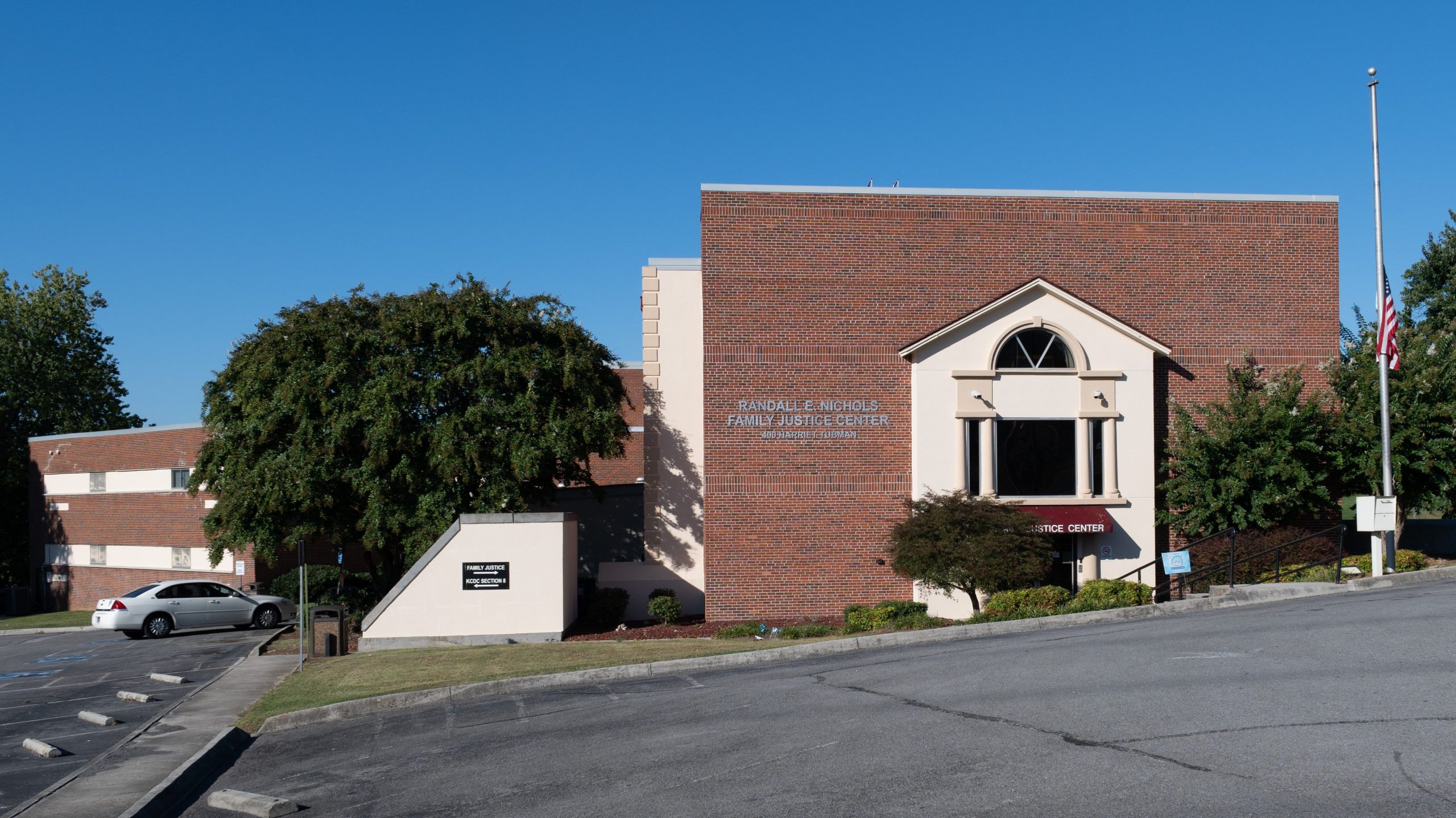 brick building with a tree and flag pole beside of it, with the name outside of it