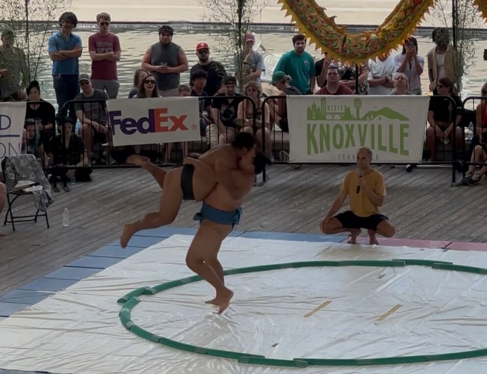 Two sumo wrestlers grapple on a mat.