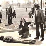 a person on the ground with people surrounding them in broad daylight