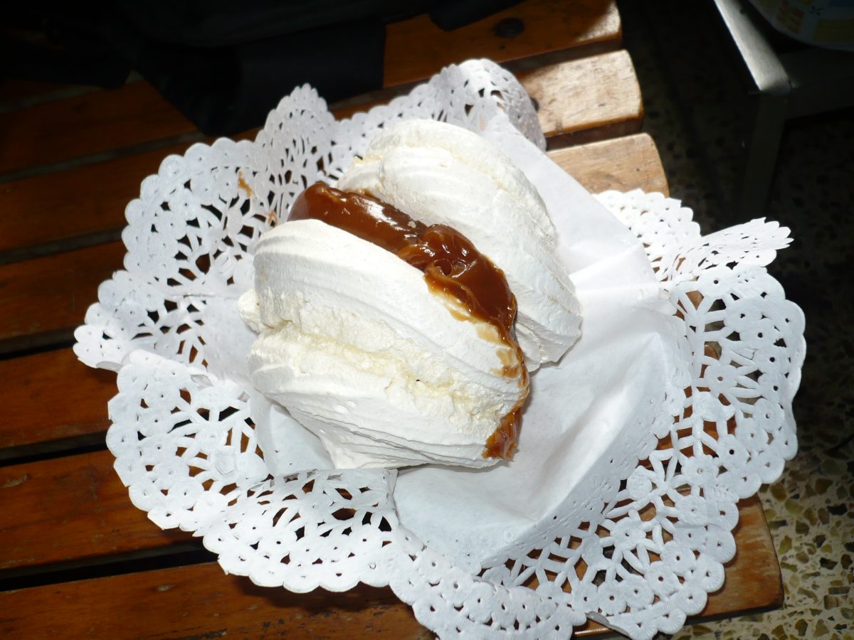 A white meringue with a dulce de leche filling served on top of a doily
