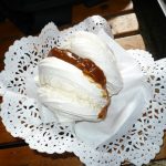 A white meringue with a dulce de leche filling served on top of a doily