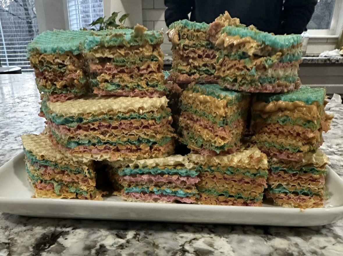 A dessert made of alternating layers of pink, white, and blue wafers and a dulce de leche cream