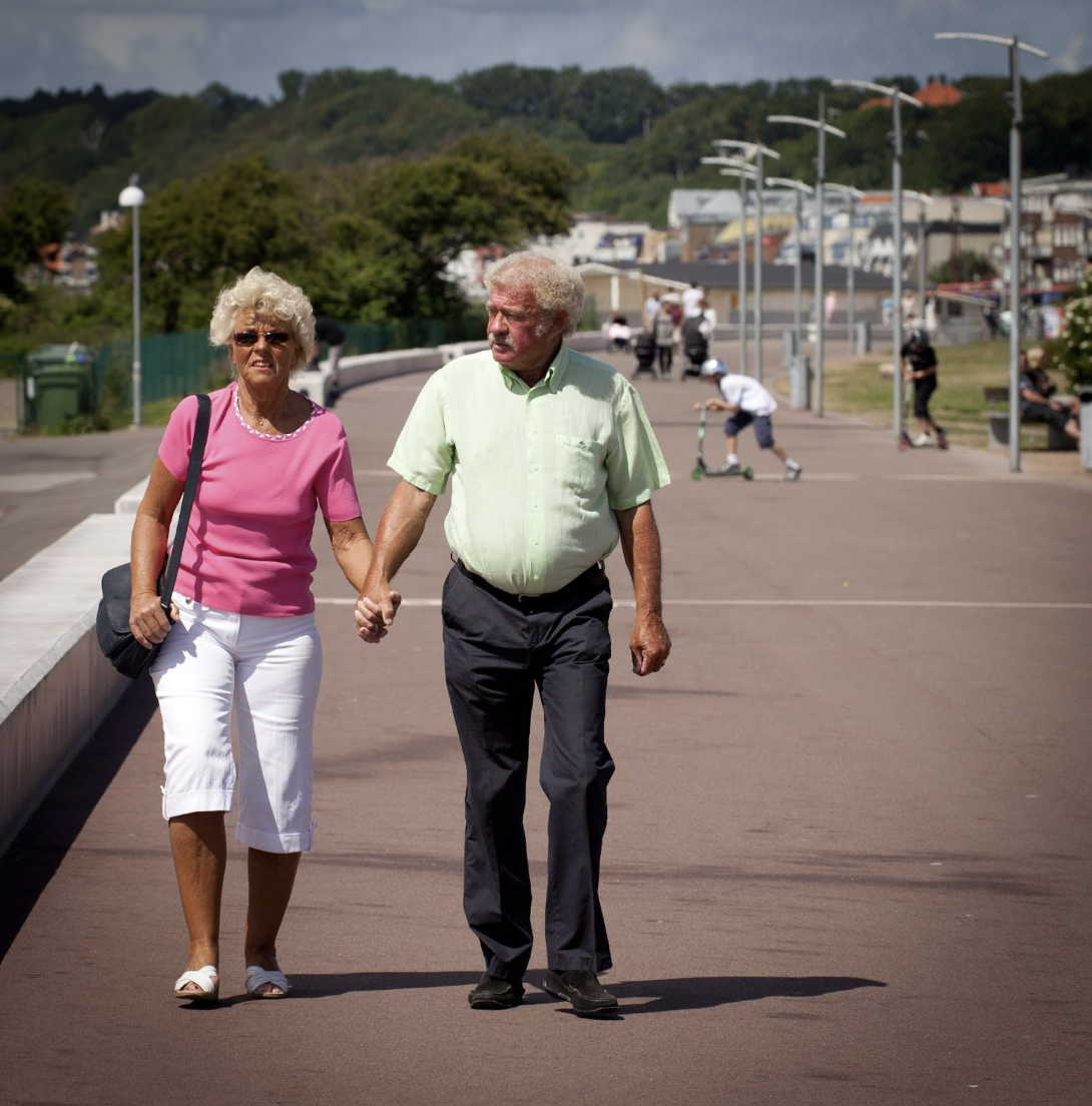 Older couple walking while holding hands.