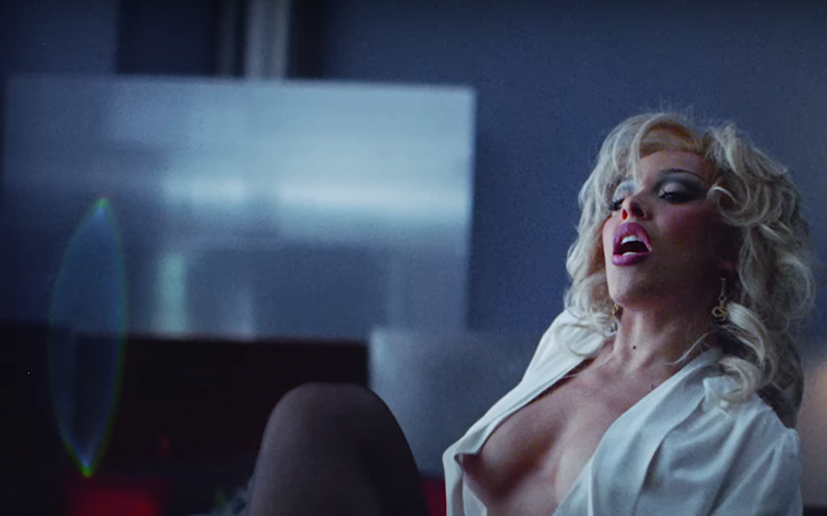 Doja Cat in a blonde wig, revealing top, and 80s makeup