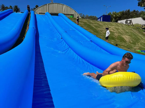 A man going down a slip-n-slide on a hill