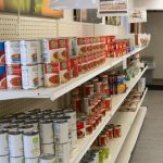 A shelf is tacked with canned foods and other non-perishable foods.