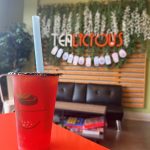 An Orange/Strawberry Fruit Tea on an orange table.