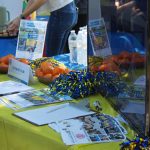 A yellow table for the Rotoract Club with promotional pamphlets and a sign up sheet.