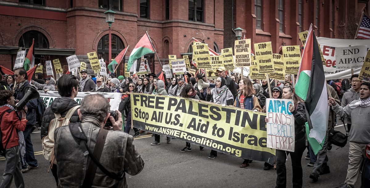 A group of protestors who hold a sign saying "Free Palestine. Stop ALL U.S. Aid to Israel."