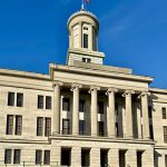 A tall building with many stairs and grand arches.