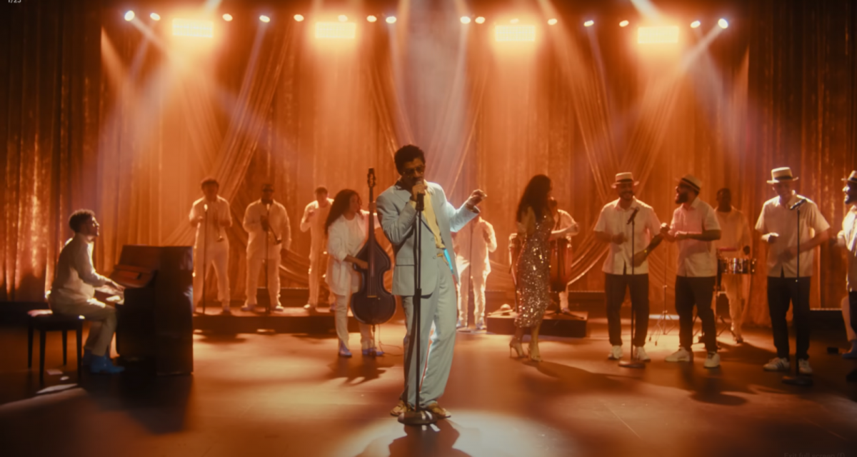 A man in a blue suit singing in front of a large band