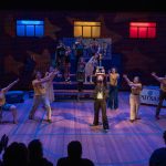 Actors perform a lively scene from The 25th Annual Putnam County Spelling Bee on a school gymnasium-themed stage.