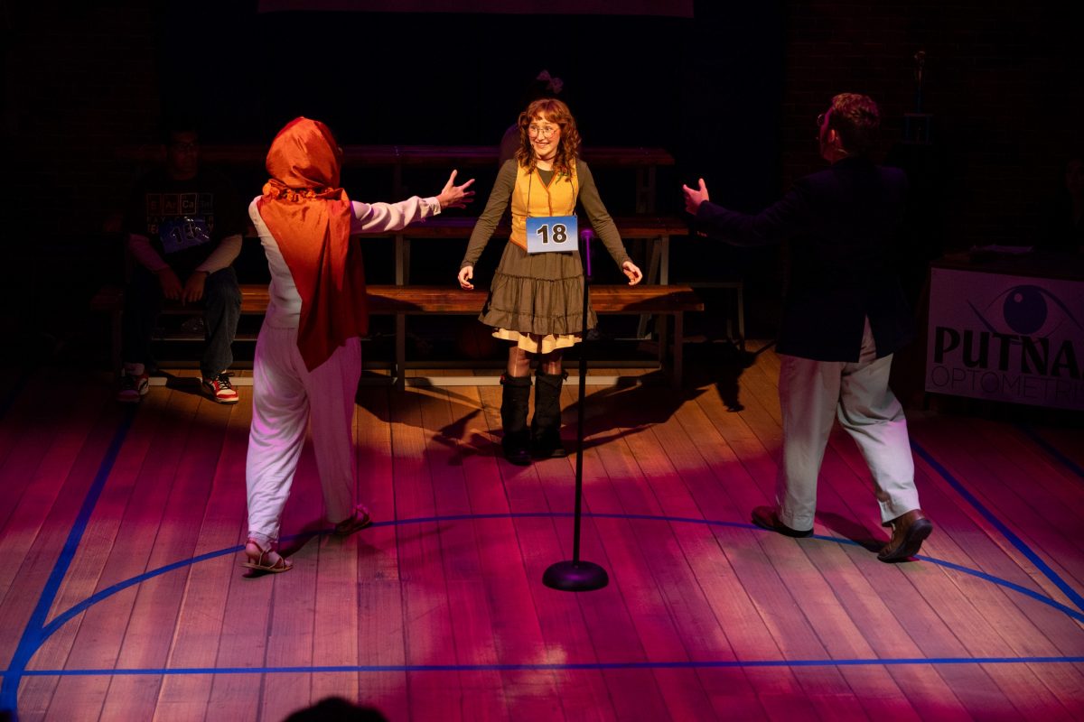 A young girl stands center stage, with a woman and man on both sides of her.