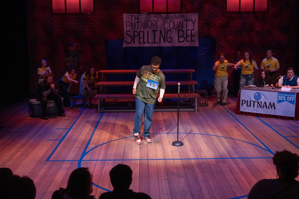 A male actor on a stage holding his foot out, surrounded by fascinated actors