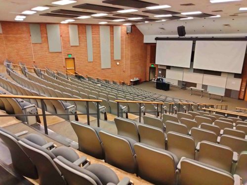 A large, empty lecture hall of a university with several chairs.