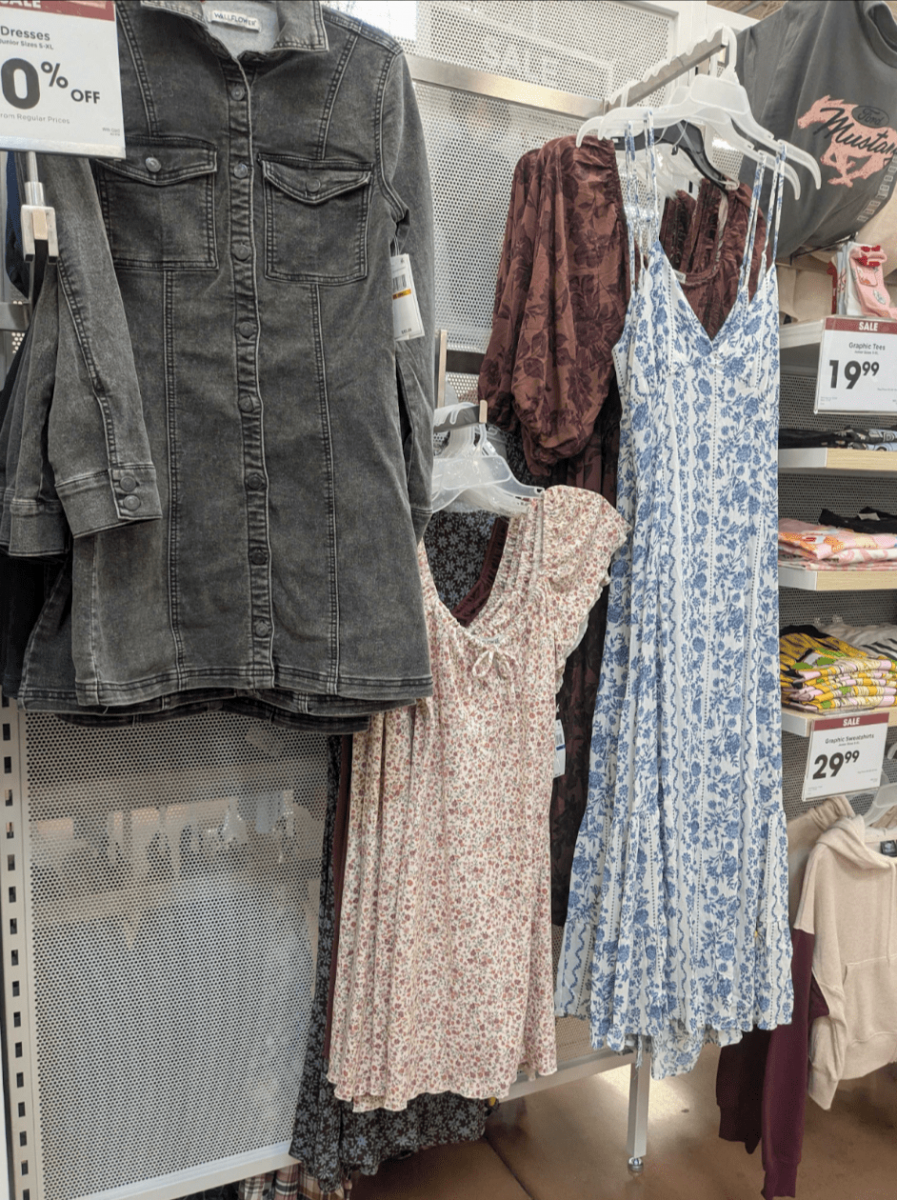Black long sleeve denim dress, shorter puff sleeve floral dress, long blue floral dress displayed in Kroger's women's clothing section
