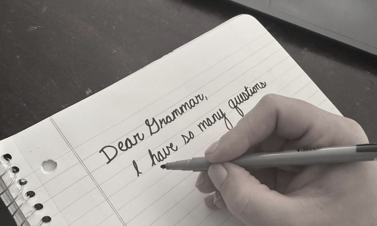 A hand holding a marker near notebook paper. The paper reads Dear Grammar, I have so many questions."