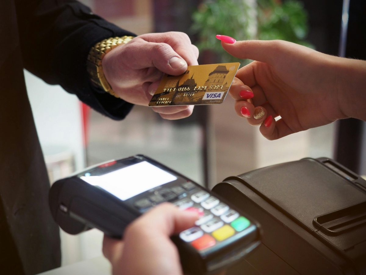 Man handing a woman his credit card to pay on a terminal