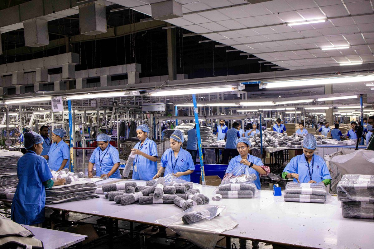 Bluecollar workers in India in uniforms wrapping up textiles.