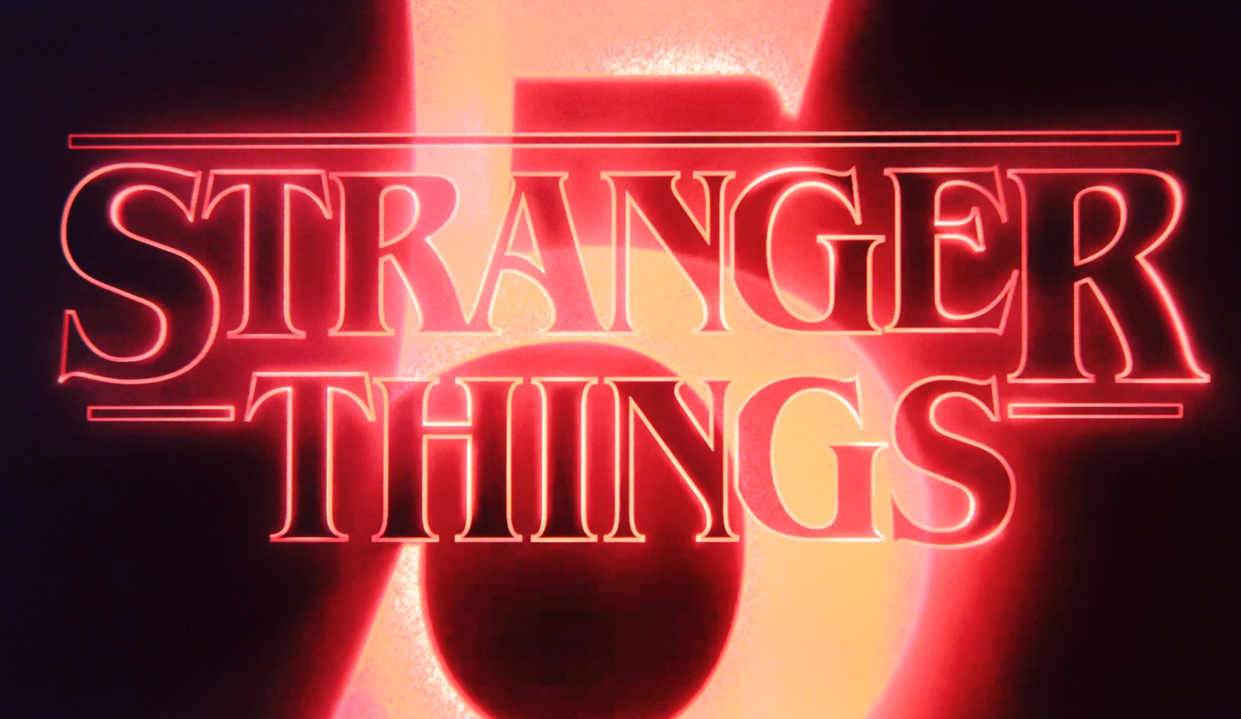 red and black logo for Stranger Things, with a bright five in the background