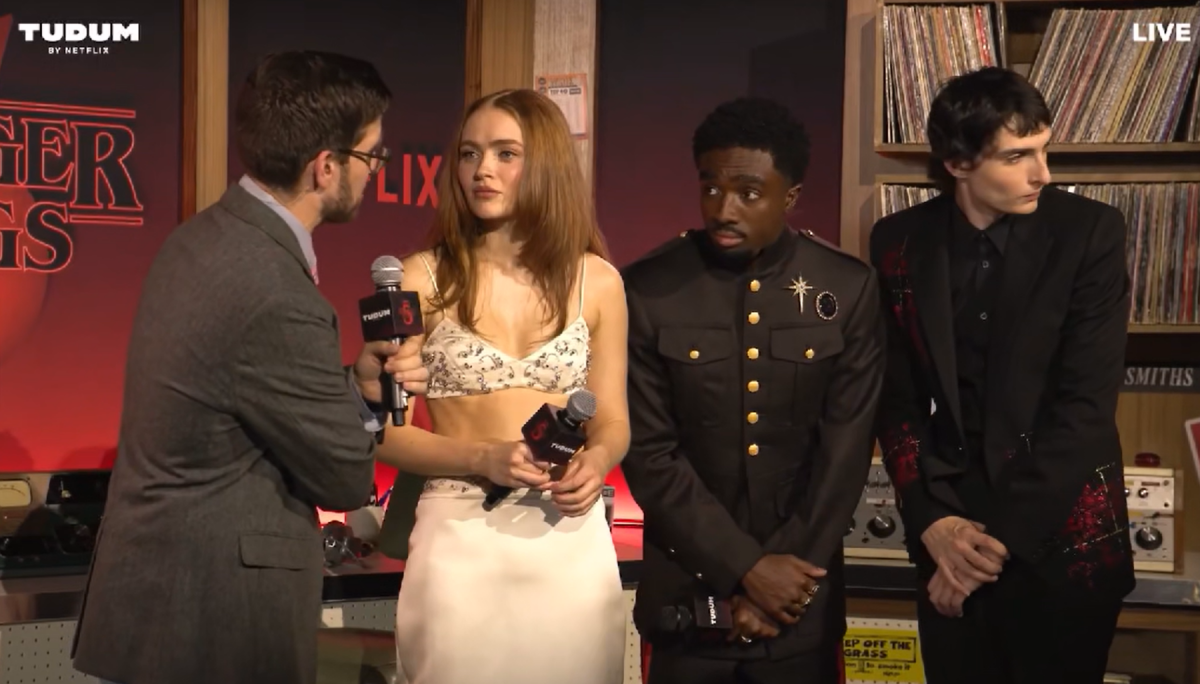 three men and a woman standing in a retro recording studio during an interview