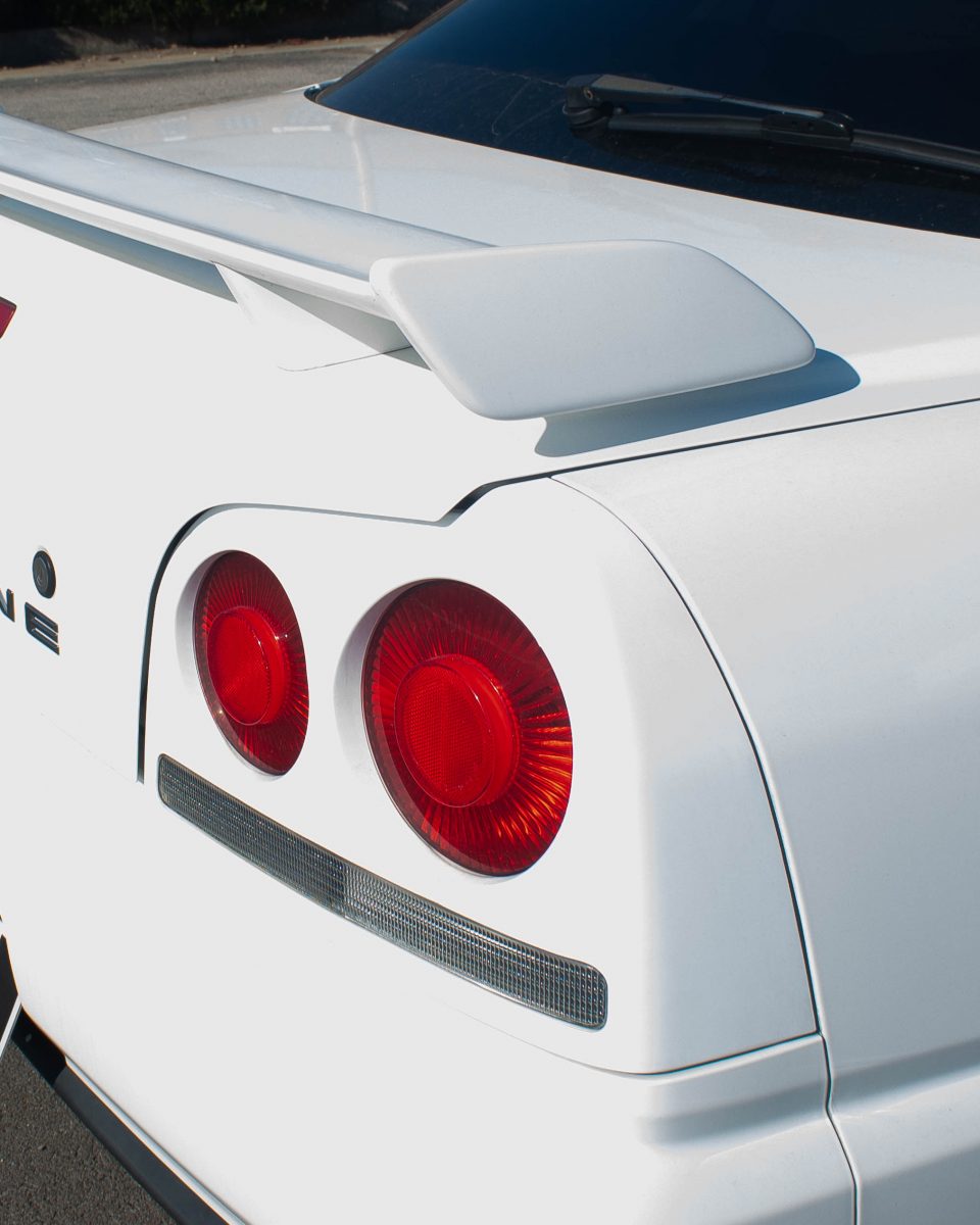 A Nissan Skyline's taillights. A spoiler is on the trunk of the car.