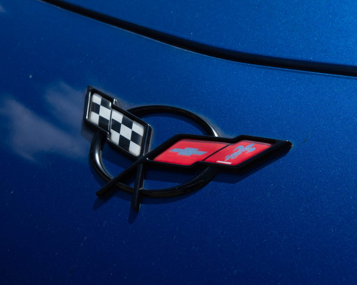 Chevrolet Corvette's emblem of two flags on a circle. The left flag has a checkered pattern, and the right flag has a Chevrolet logo.