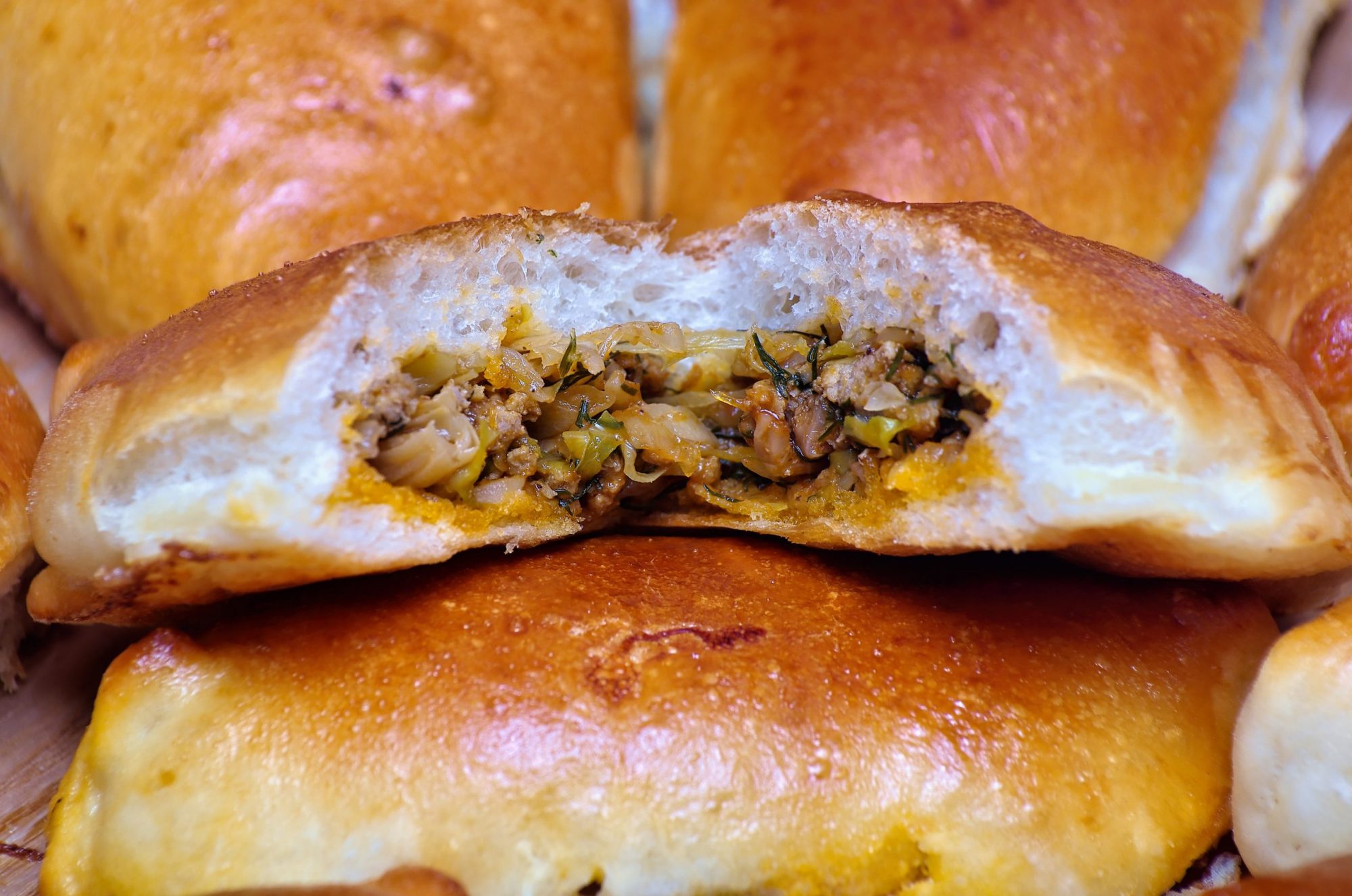 A close-up of several meat pies, with one in the center that had a bite taken out