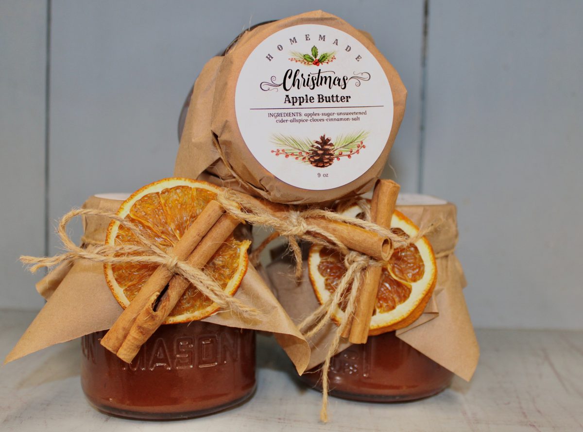 three jars of apple butter with freeze dried oranges and cinnamon sticks attached