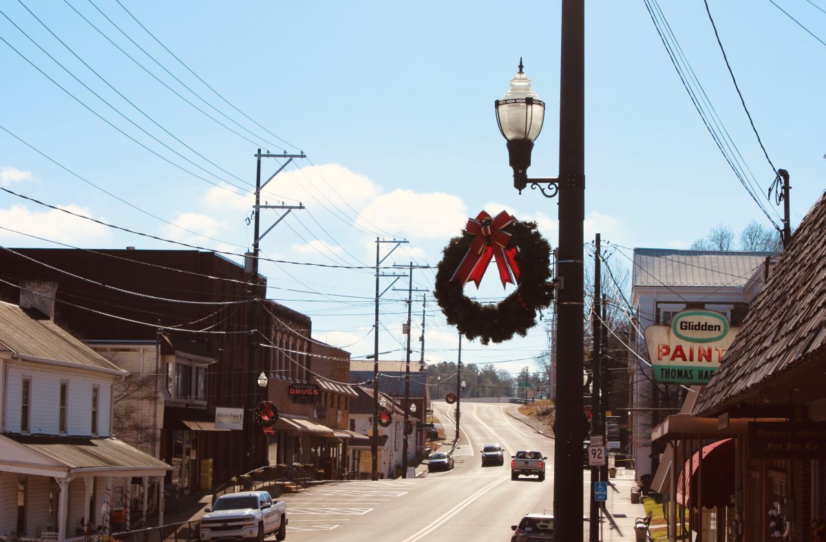 street with stores on both sides of the road with Christmas decor on light poles