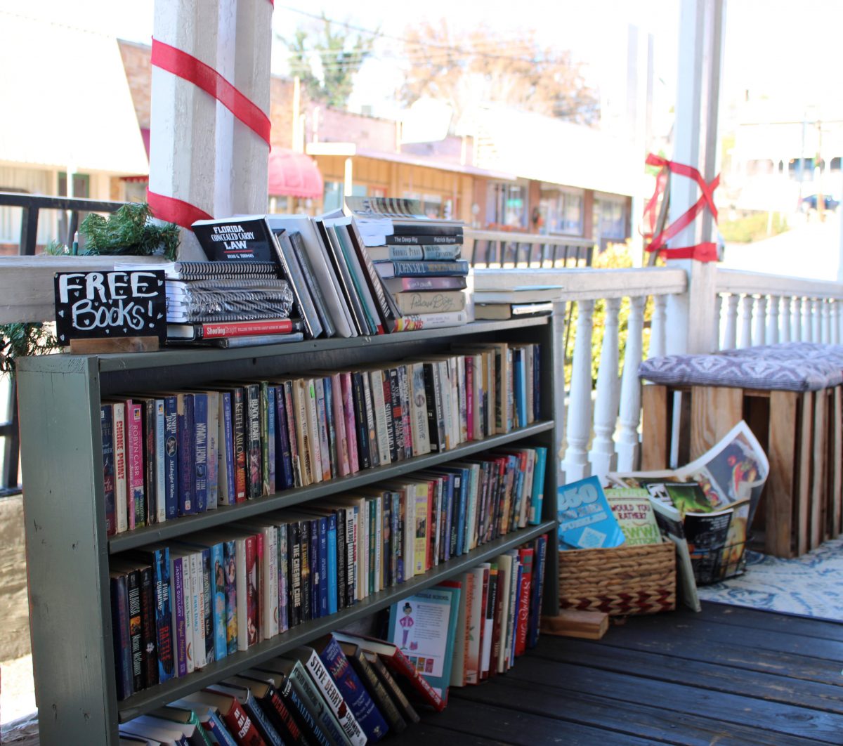 an overflowing three-tiered bookshelf with a "free books" sign on top