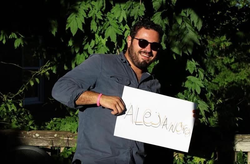 Alejandro holding a sign that says “Alejandro”