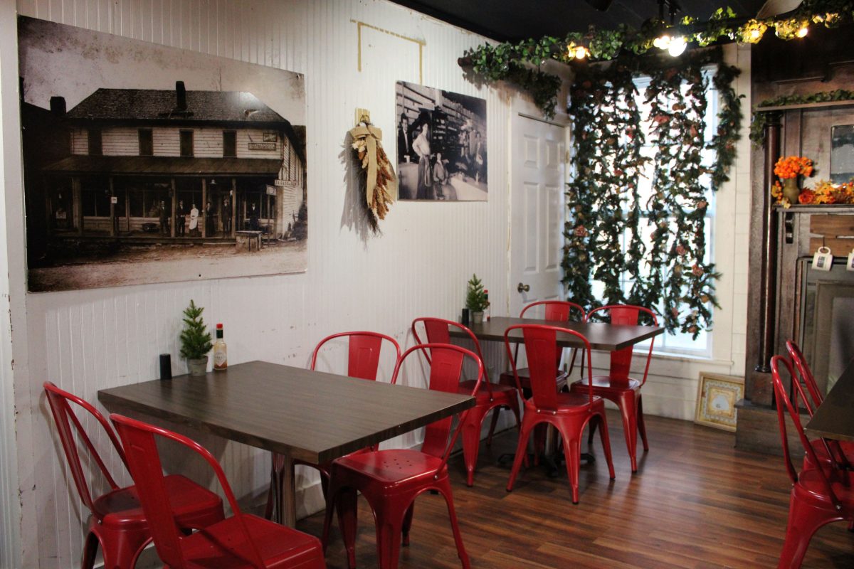 a cozy room with red chairs and wood tables next to a fireplace