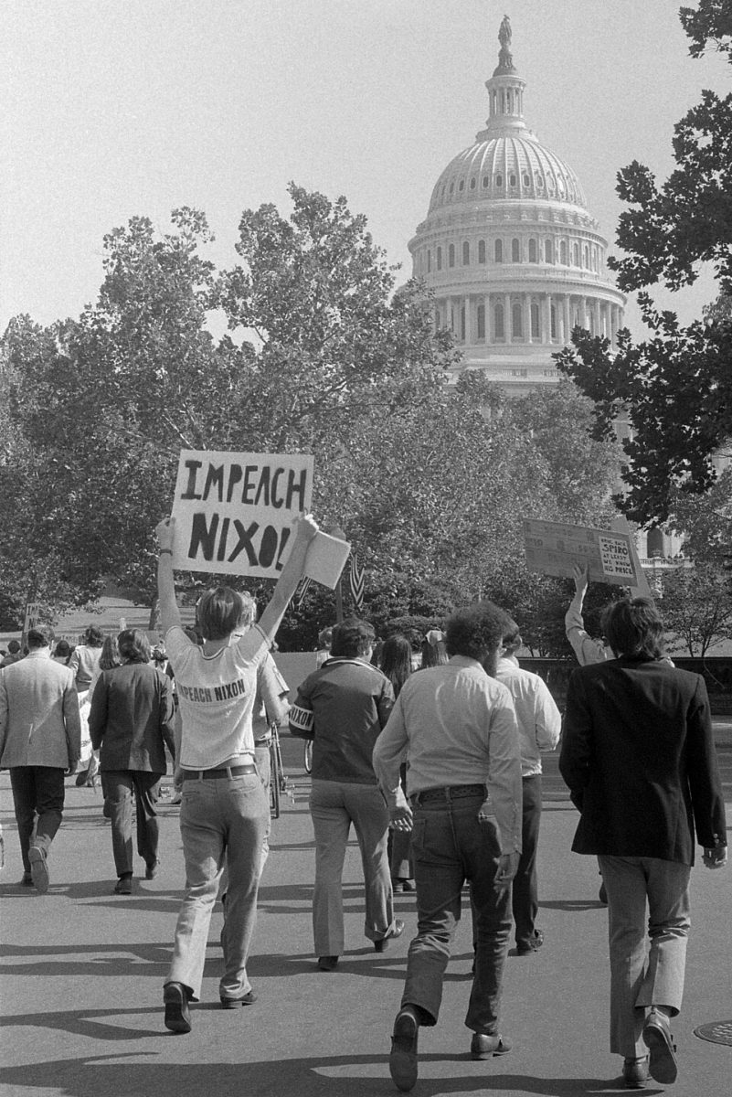 A number of protestors pictured near the Capitol Building, with signs and shirts labelled “Impeach Nixon”.