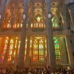 A wall of various stained glass windows with columns in between
