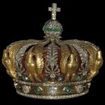 A crown with green and golden jewels.