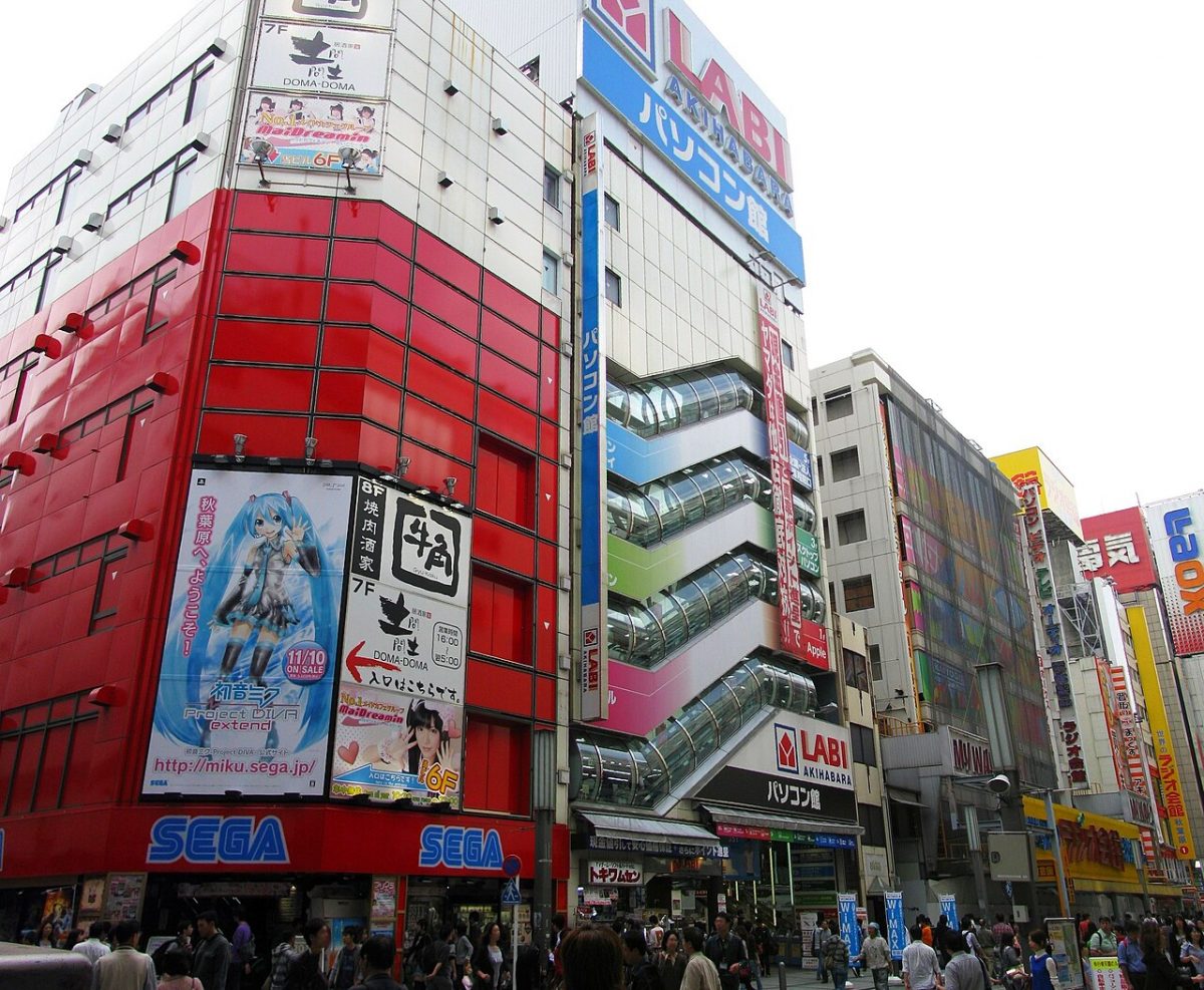A crowd of people walking past tall buildings.