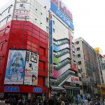 A crowd of people walking past tall buildings.