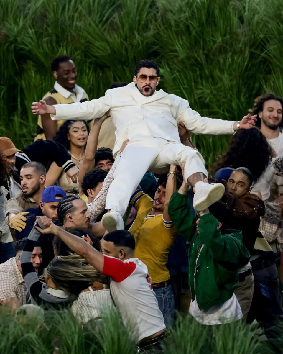 Bad Bunny singing as his backup dancers hold him