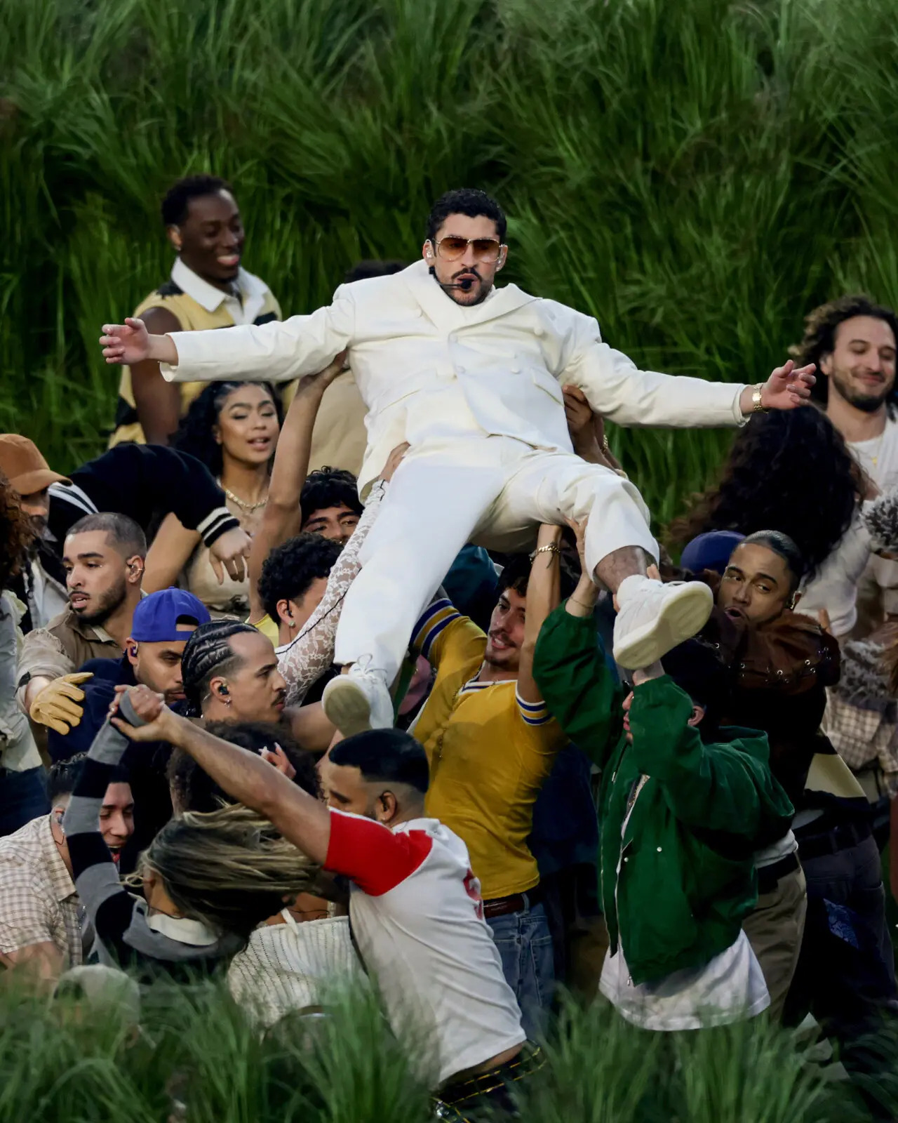 Bad Bunny singing as his backup dancers hold him